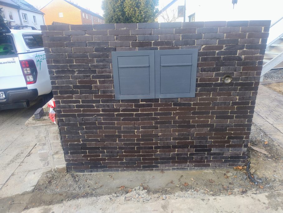 Verklinkerte Mauer mit zwei integrierten Briefkästen und Klingel.