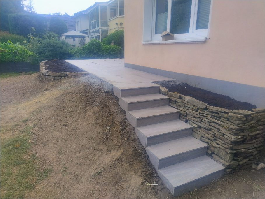 Keramikplatten mit einer Treppe und angrenzendem Blumenbeet